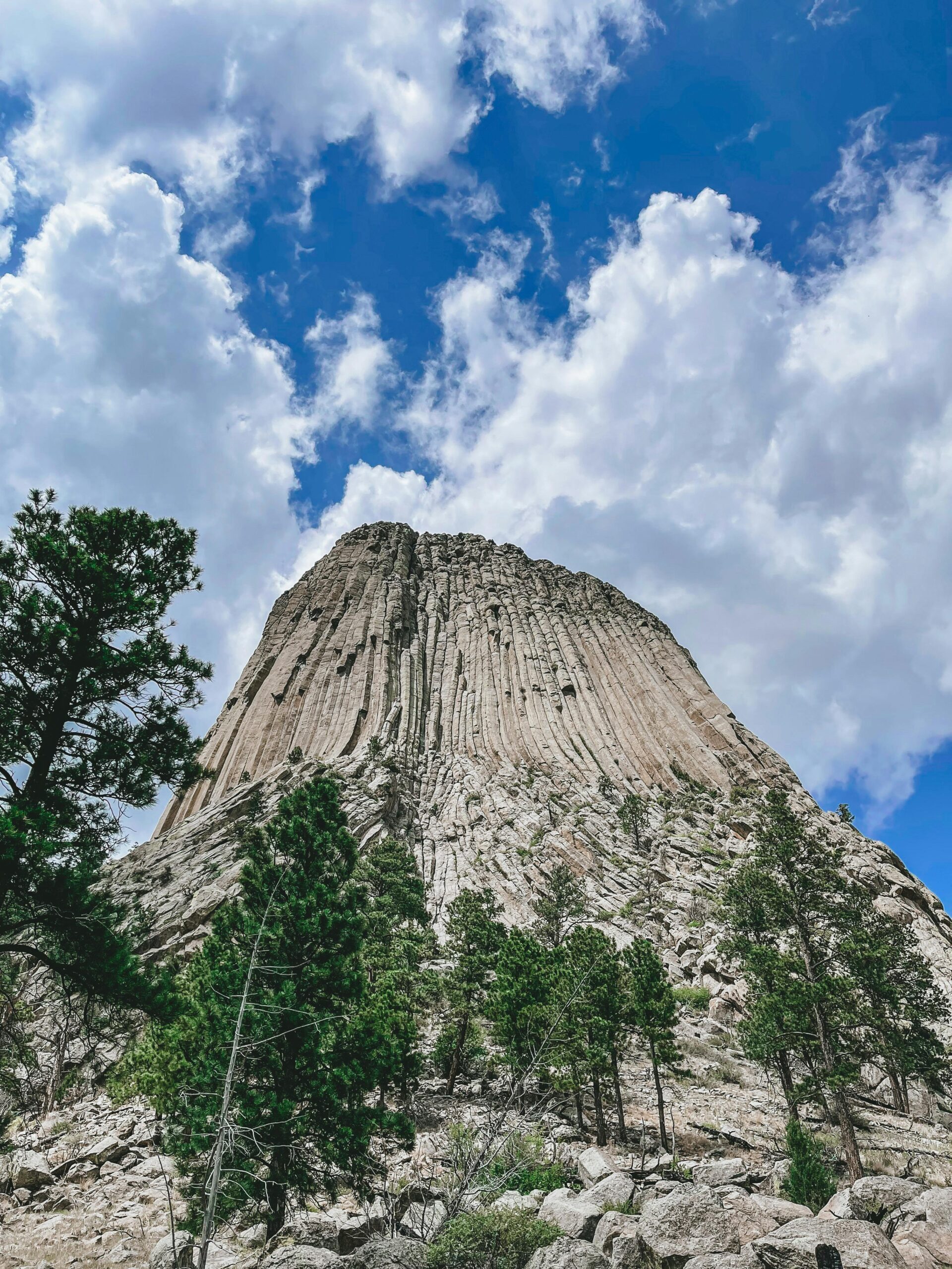 Stunning view of Devils Tower against a vibrant blue sky with fluffy clouds.