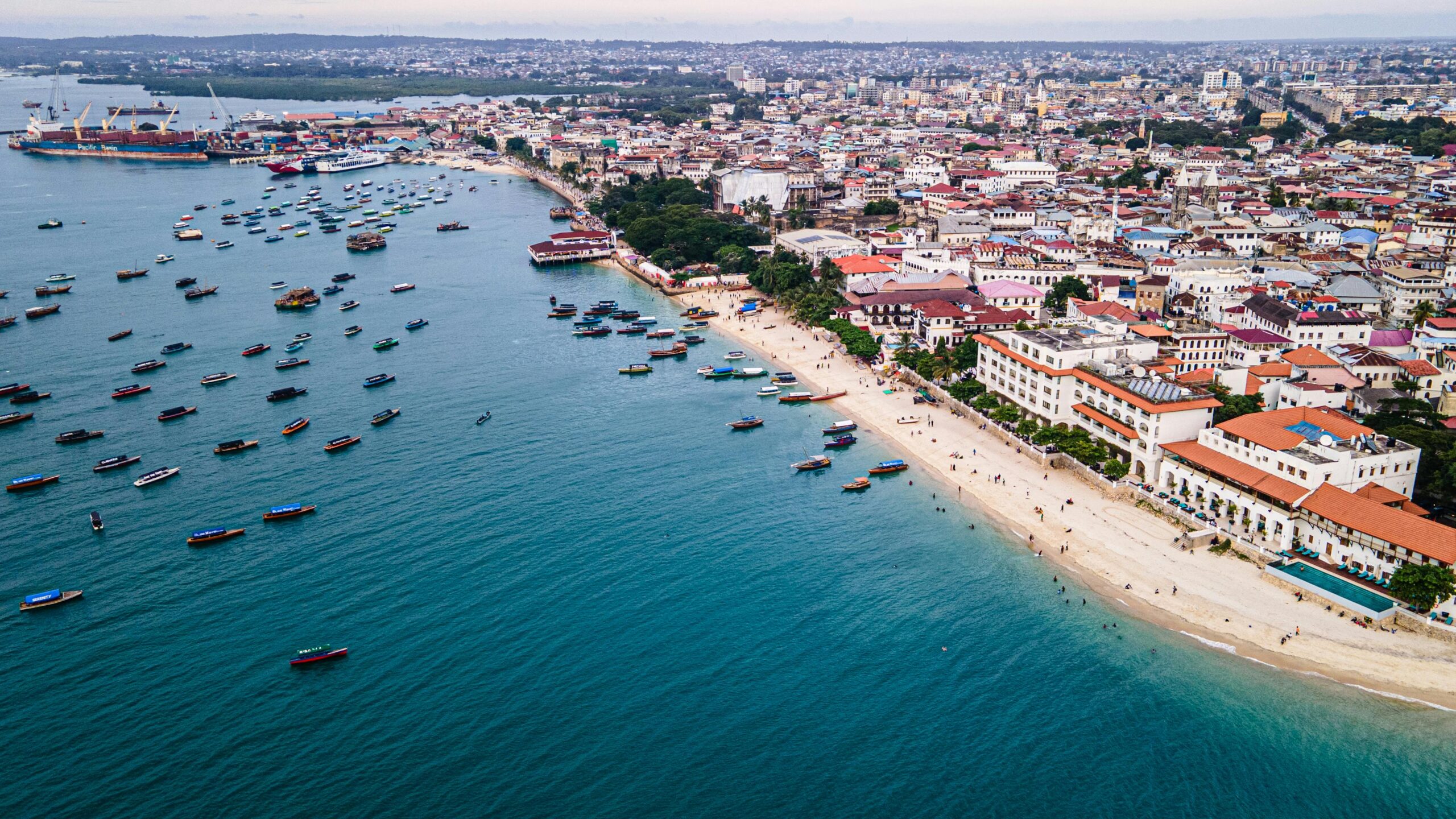 Stunning aerial view of Zanzibar Stone Town's coastline with boats and vibrant cityscape.