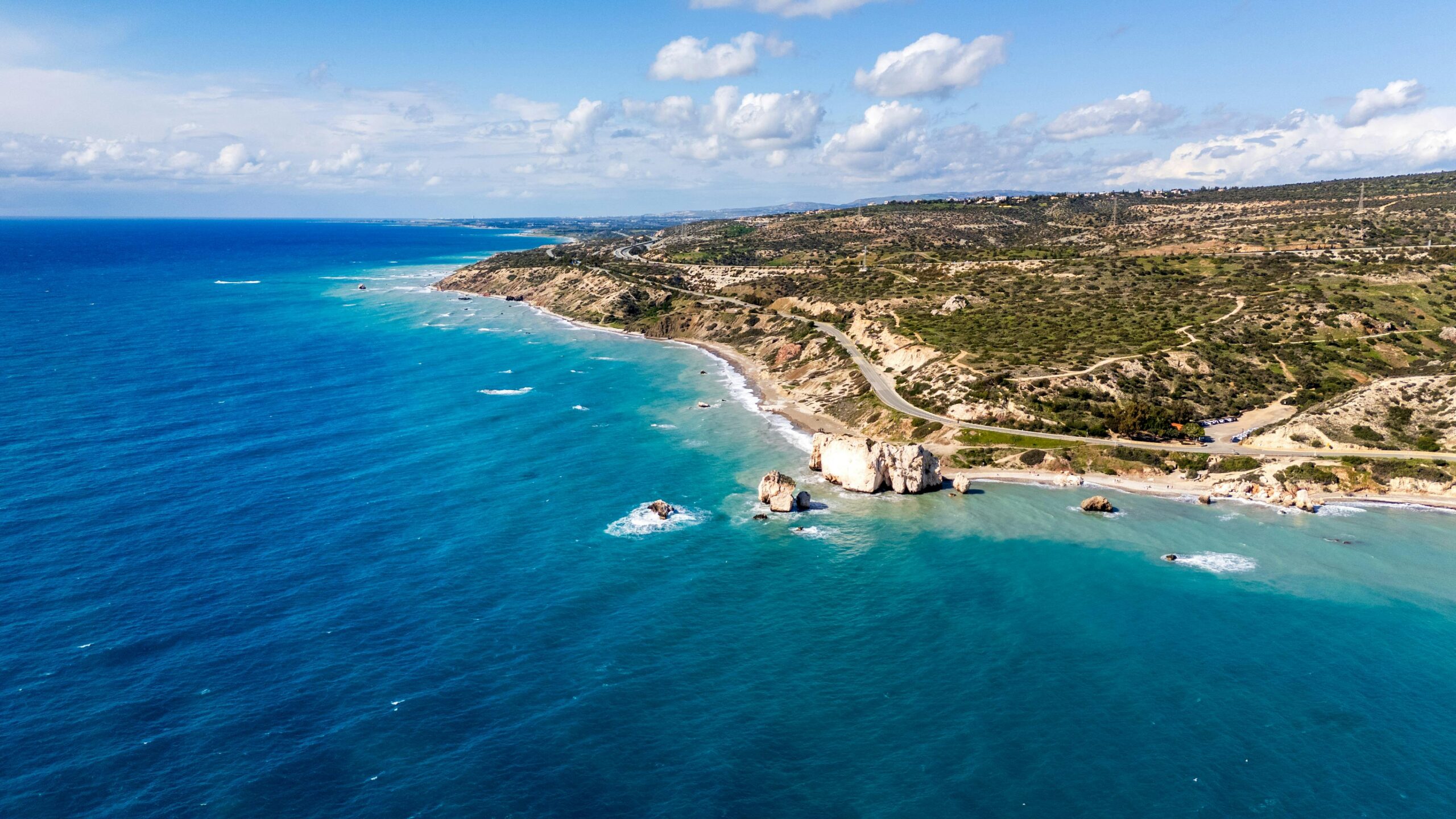 Stunning aerial photograph of Aphrodite's Rock on Cyprus coastline, surrounded by vibrant blue waters.