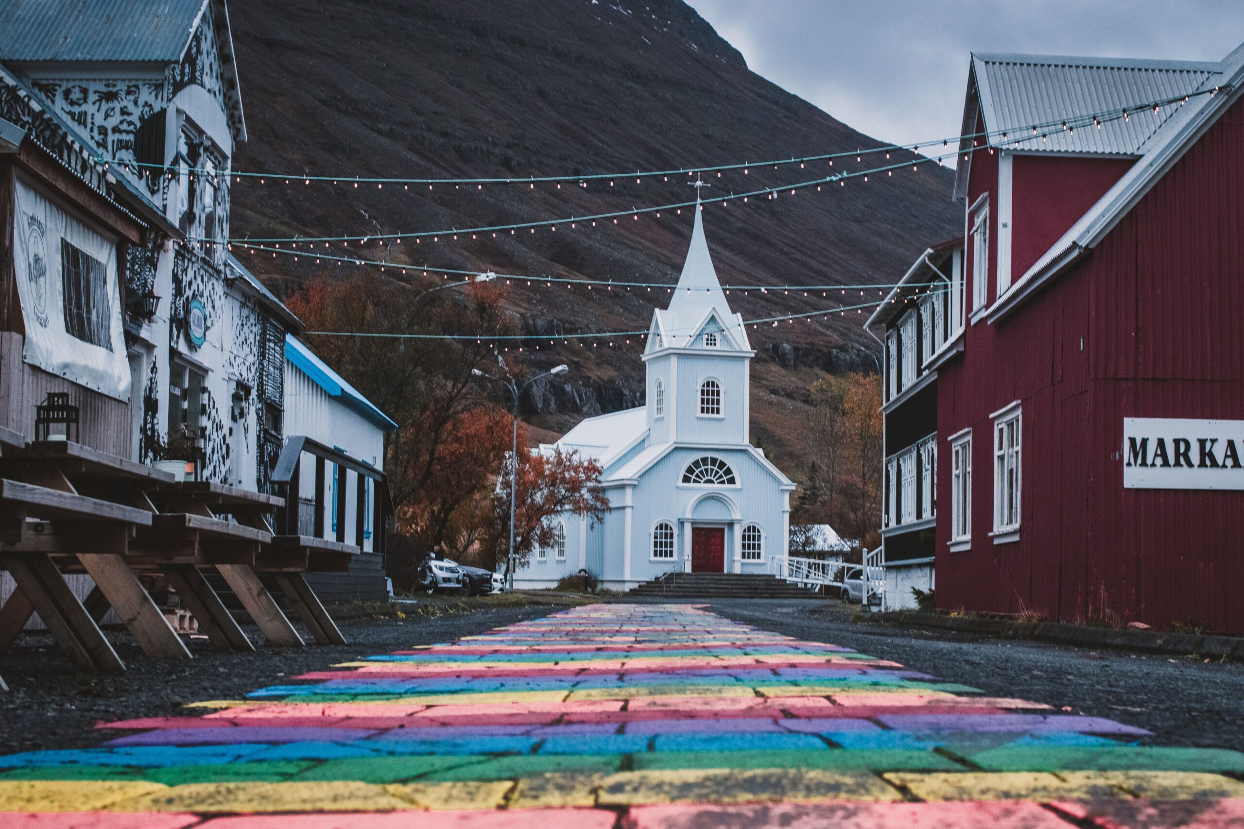 Charming view of a colorful street leading to a church in Seyðisfjörður, Iceland.